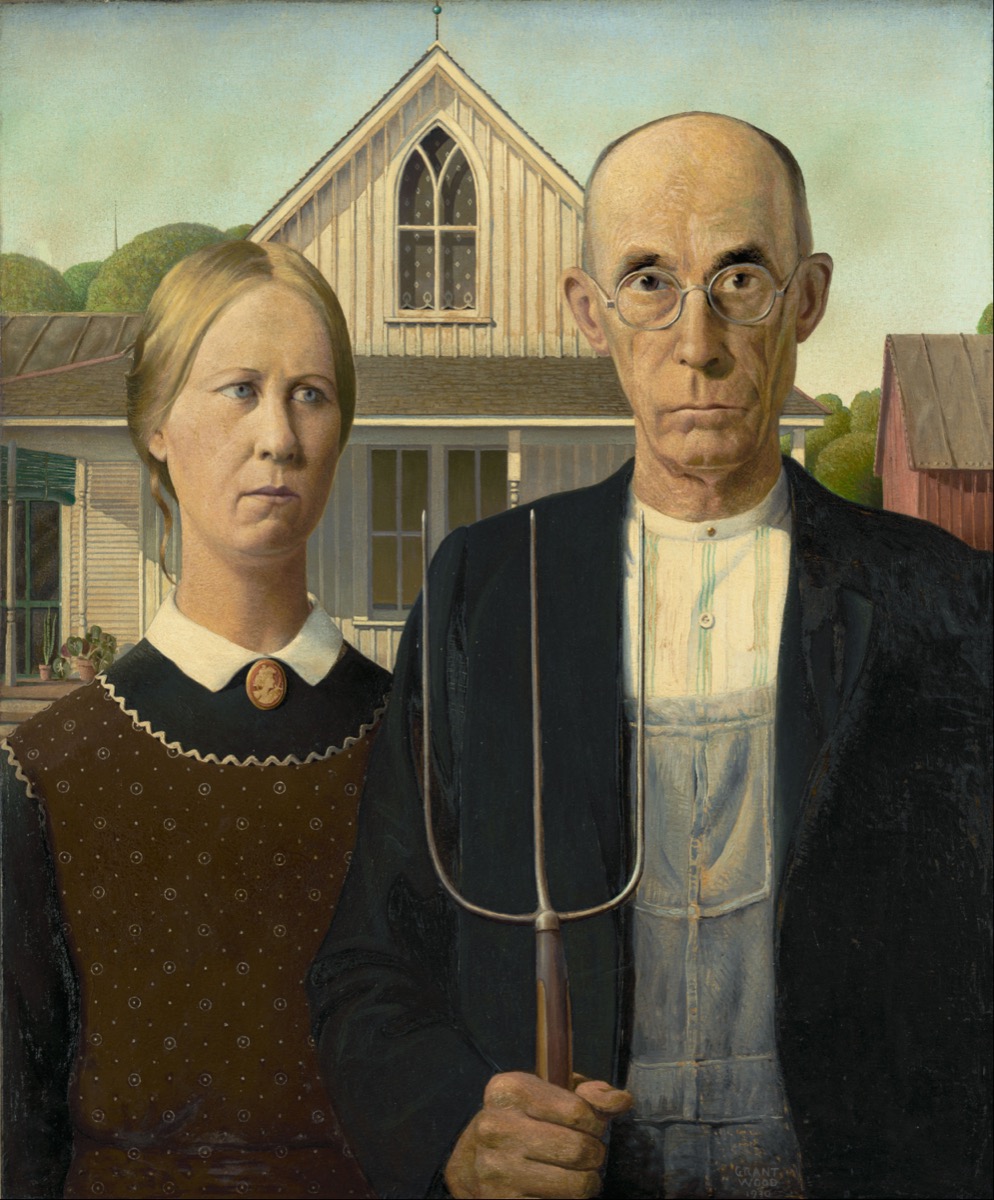 Grant Wood's original 1930 oil painting American Gothic, showing the two figures posed in front of the pointed-window house, as displayed at the Art Institute of Chicago