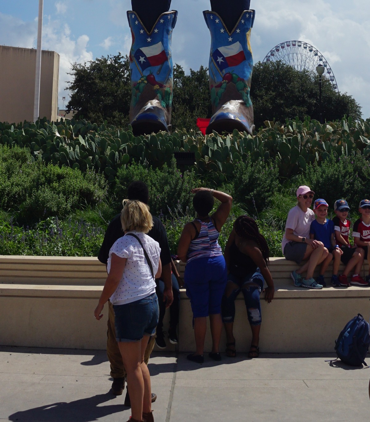 Big Tex's giant cowboy boots towering over fairgoers at the State Fair of Texas, showing the scale of the statue