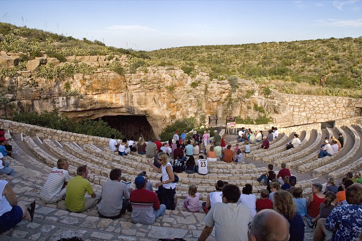 Visitors seated on the stone benches at the Bat Flight Amphitheater at Carlsbad Caverns National Park at dusk, waiting for the bat flight, ranger nearby