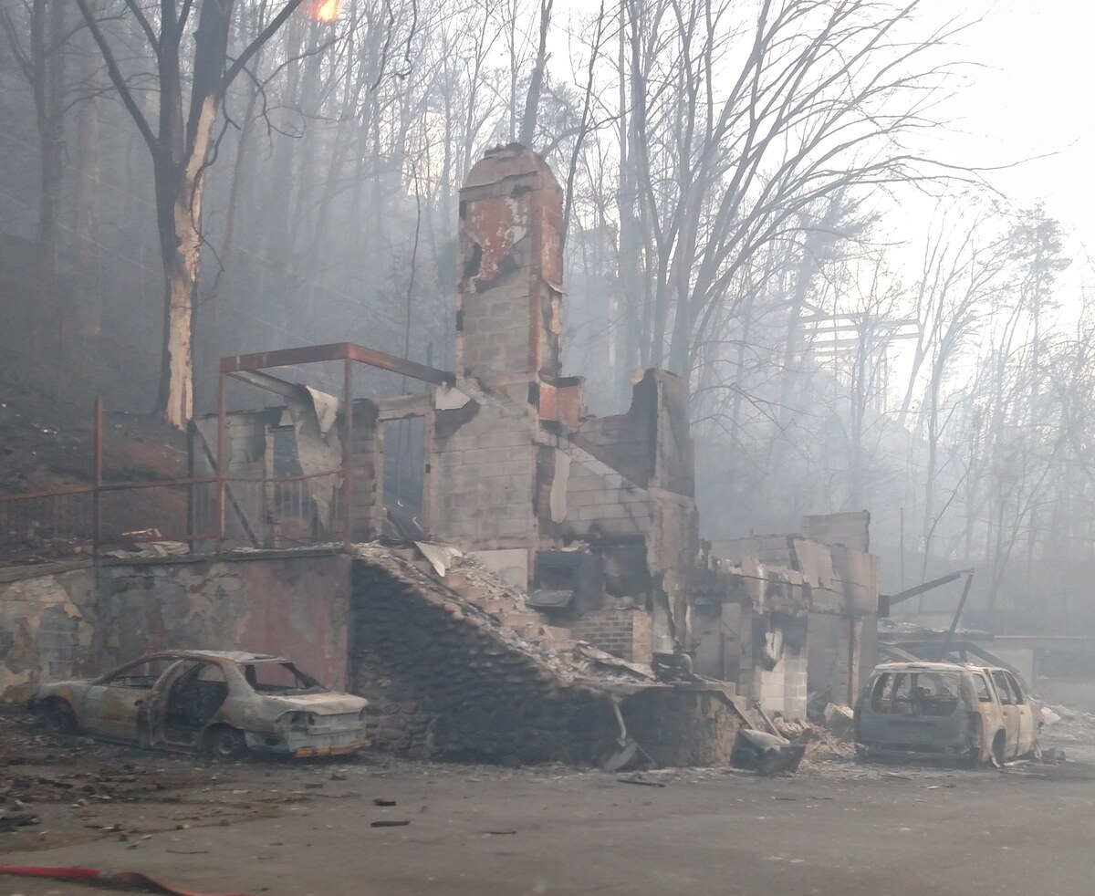 A burned-out house and two burned-out cars in smoke after the November 2016 Gatlinburg, Tennessee wildfires