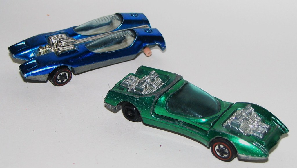 Two original 1968-dated Hot Wheels Redline die-cast cars in metal-flake paint on a plain background, red-stripe tyres clearly visible