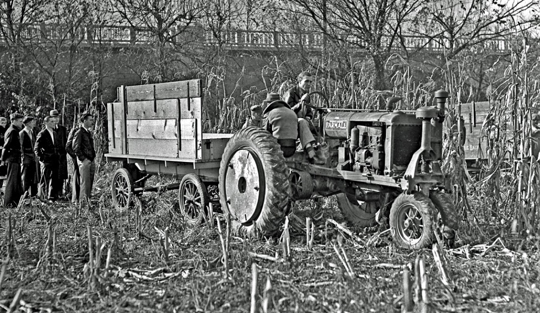 A Farmall tractor pulling a corn-husking contest wagon down the rows at a 1938 Franklin County, Ohio contest, with spectators watching from the edge of the field