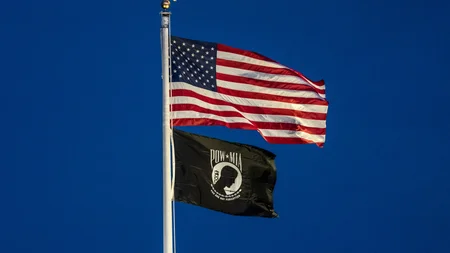 The POW/MIA flag flies at post offices, a Vietnam-era symbol. The gaunt face on it is real. Designer