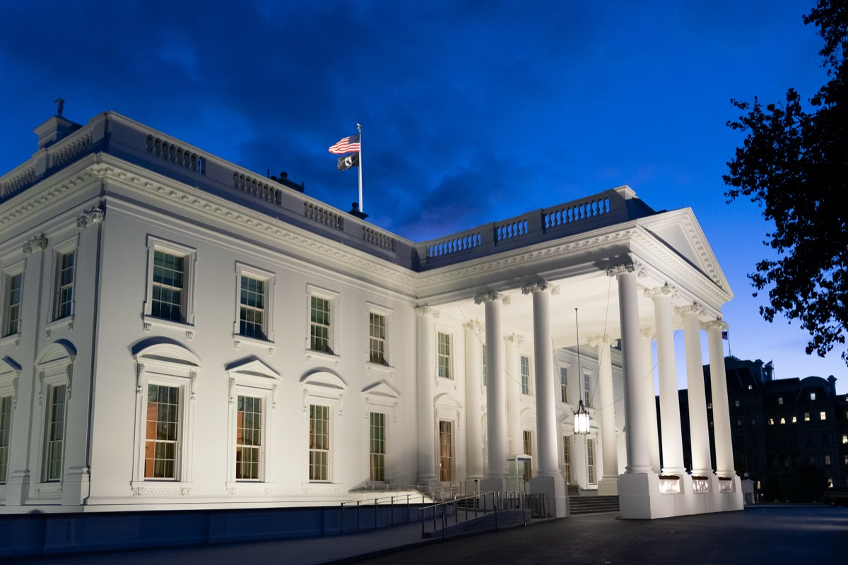 Wide shot of the POW/MIA flag flying alongside the American flag over a public building, memorial, or the U.S. Capitol, showing the scale and setting of its official display