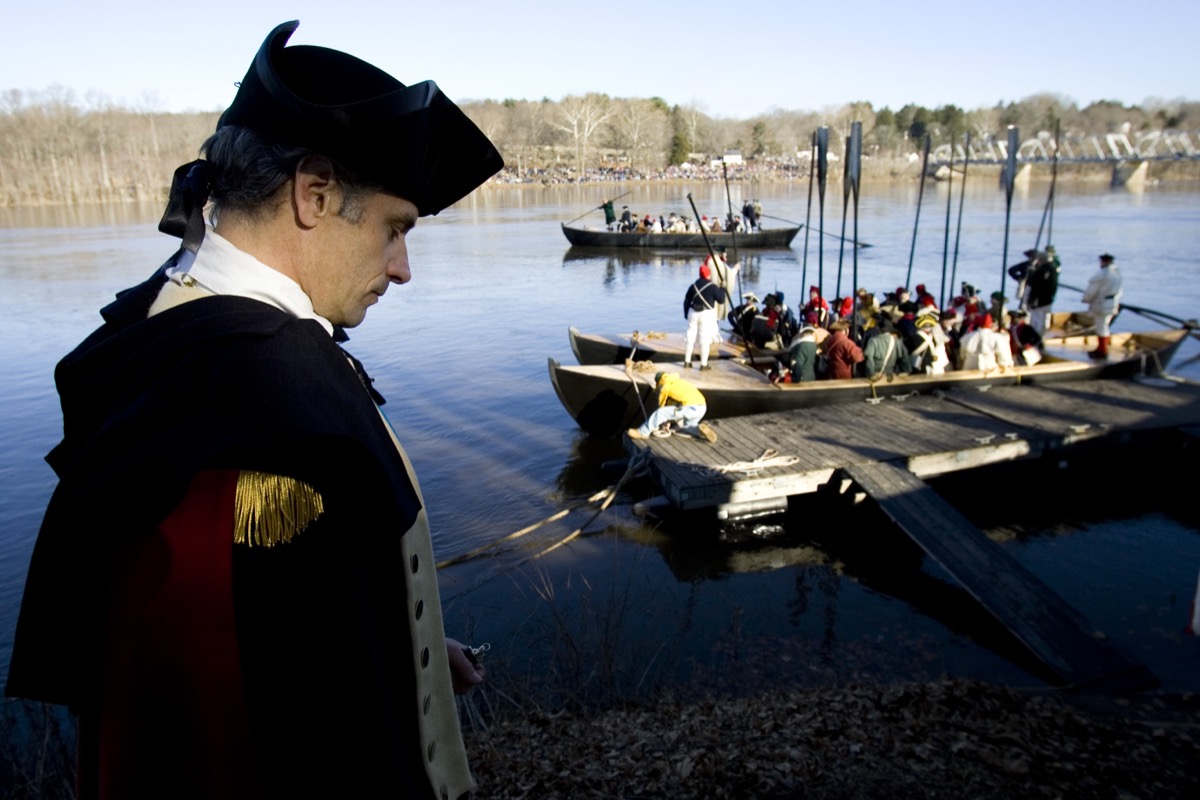 Costumed Revolutionary War reenactors board a replica Durham boat on the Delaware River as a reenactor playing George Washington looks on, during the annual Christmas Day crossing reenactment
